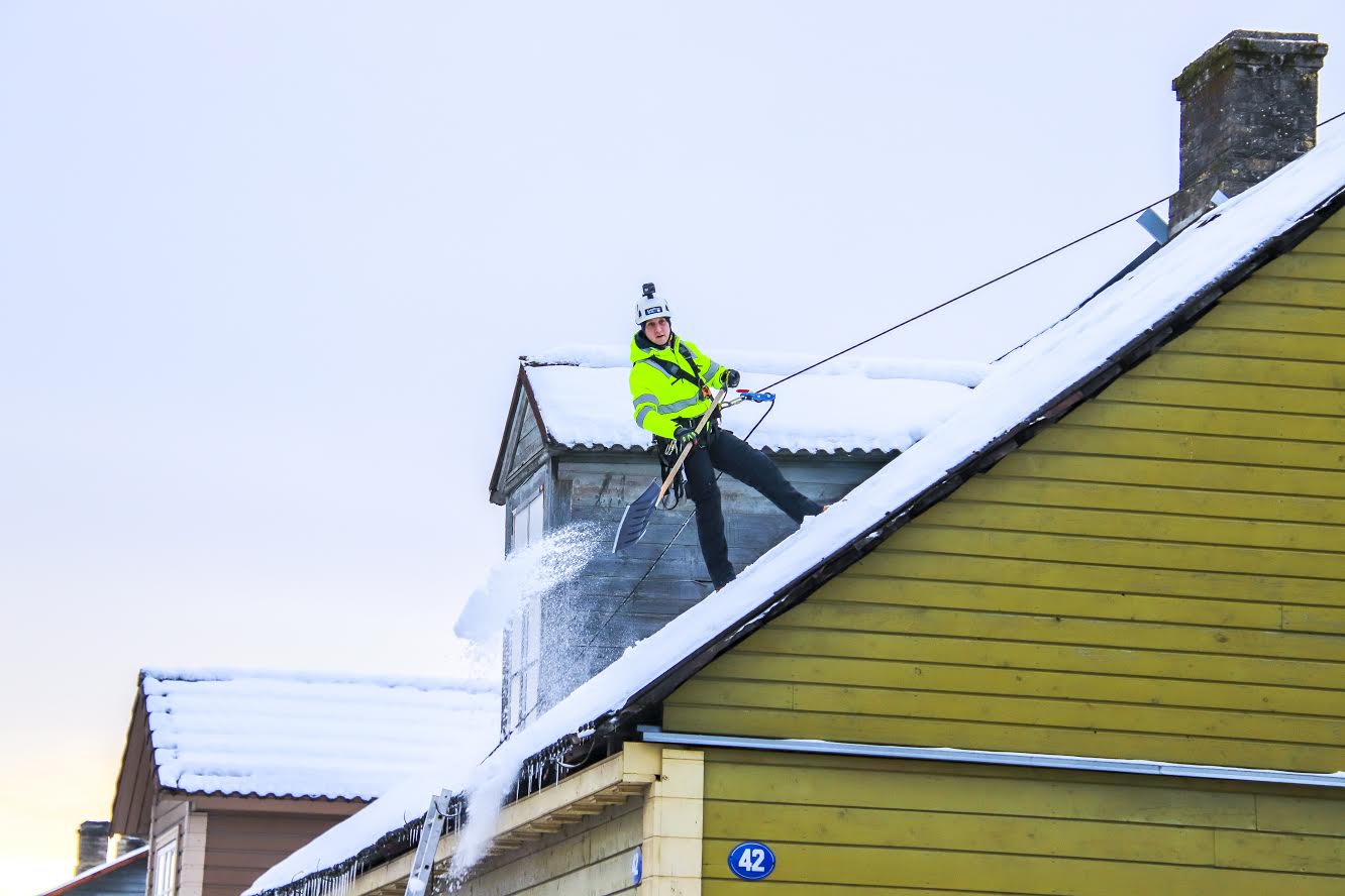 Juri Mirontšuk OÜst Rope Spiders pääseb oma töövarustusega ligi igale katusele. Mehe sõnul tasuks juba 20–25sentimeetrise lumepaksuse puhul olla valmis lund koristama, sest sulailmadega muutub lumi raskemaks ja tekib jää. Eile ronis mees Kreutzwaldi tänaval asuva OÜ-le Edepol kuuluva hoone katusele, et olukorda hinnata. Foto: AIGAR NAGEL