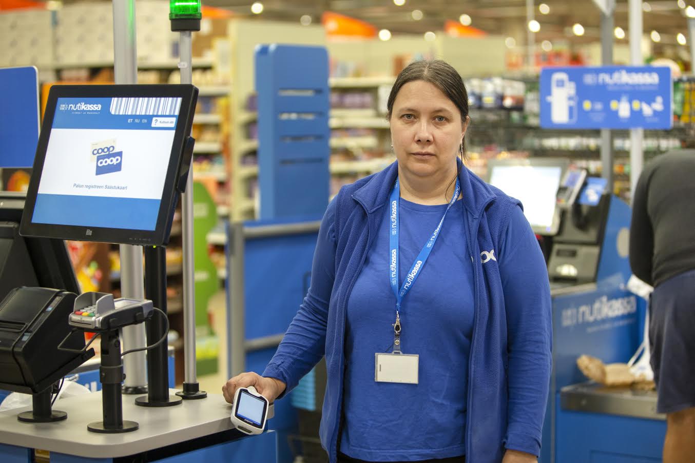 Võru Maksimarketi teenindaja Terje Piirisalu abistab kliente iseteeninduskassades ostlemisel. Foto: AIGAR NAGEL