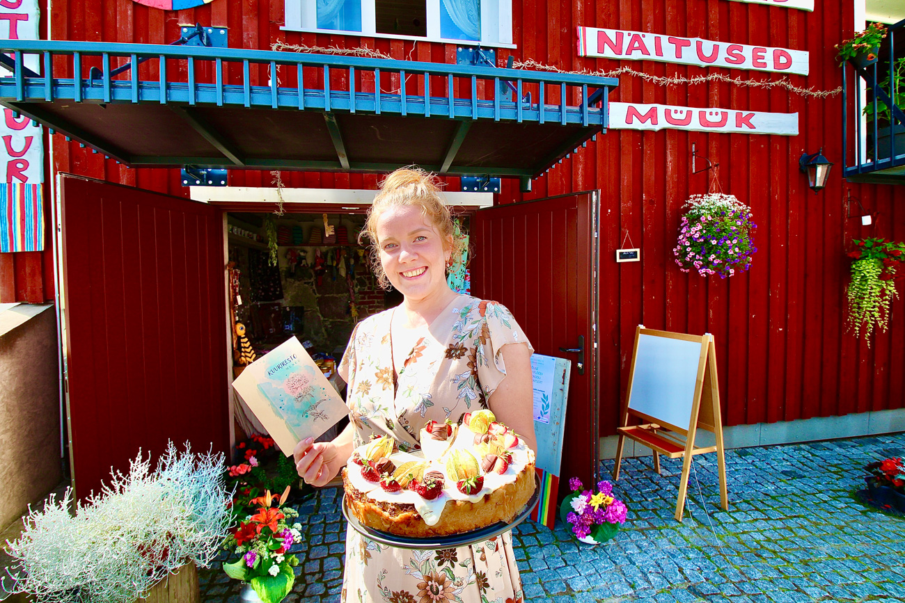 Kuuriresto perenaine Mari-Liis Henk rõõmustab, et kuuriresto kohe esimesest päevast palju inimesi kohale meelitas ning demonstreerib kuuriresto kooki ja menüükaarti. Koogitükk maksab näiteks 3,5 ja käsitöölimonaad neli eurot. Foto: KALEV ANNOM