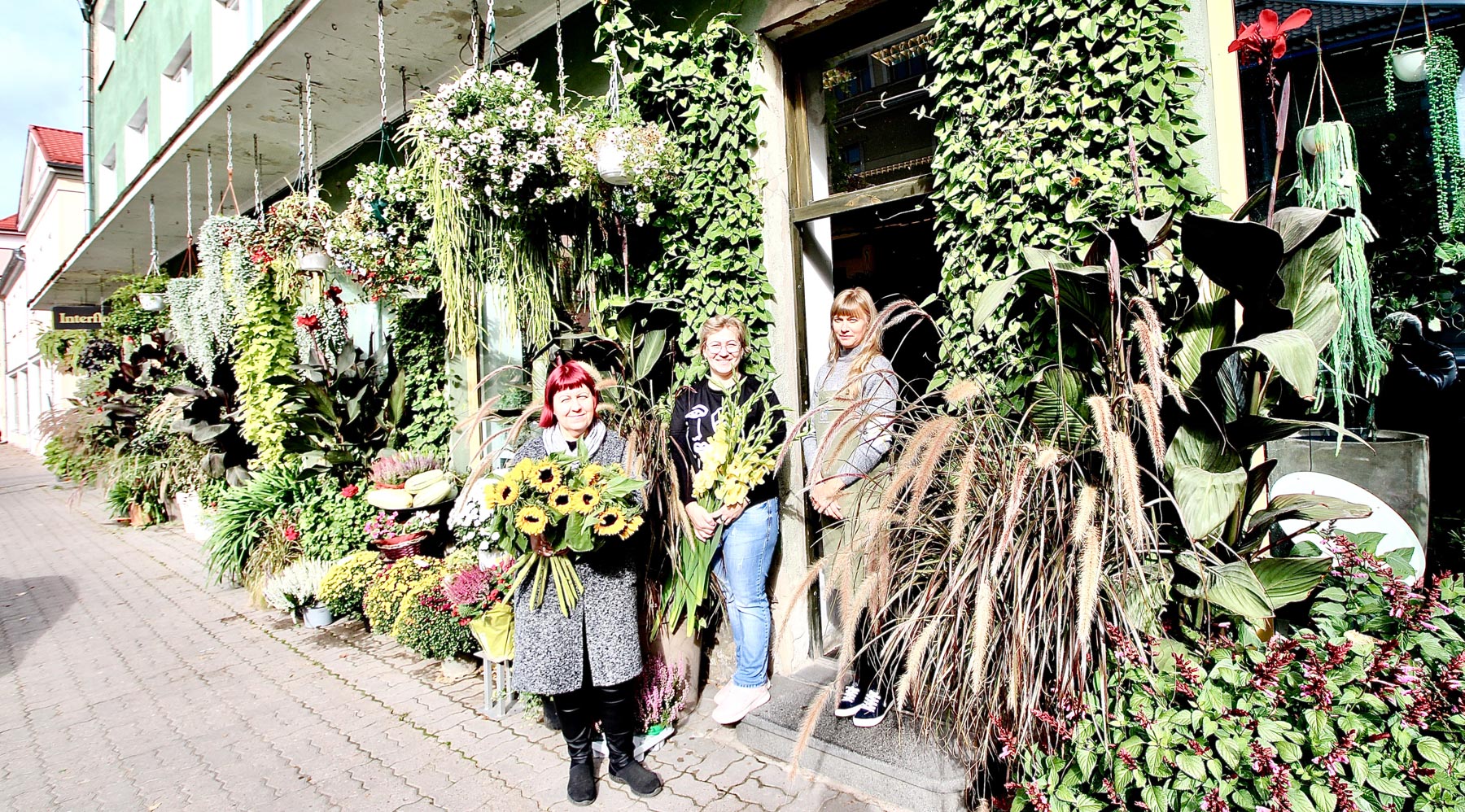 See pilt on tehtud sel nädalal Võrus Leeri lillesalongi ees, kus õnnestus pildile meelitada vabaõhu lillenäituse tegijad Diana Kirspuu (töötanud salongis 12 aastat, vasakult), Ene Toomemägi (22) ja Riina Viitkar (22). Pildilt puudub Liisi Eerik (6). Nii pikk ei olevat lillede väljapanek varasematel aastatel olnud. FOTOD: Kalev Annom