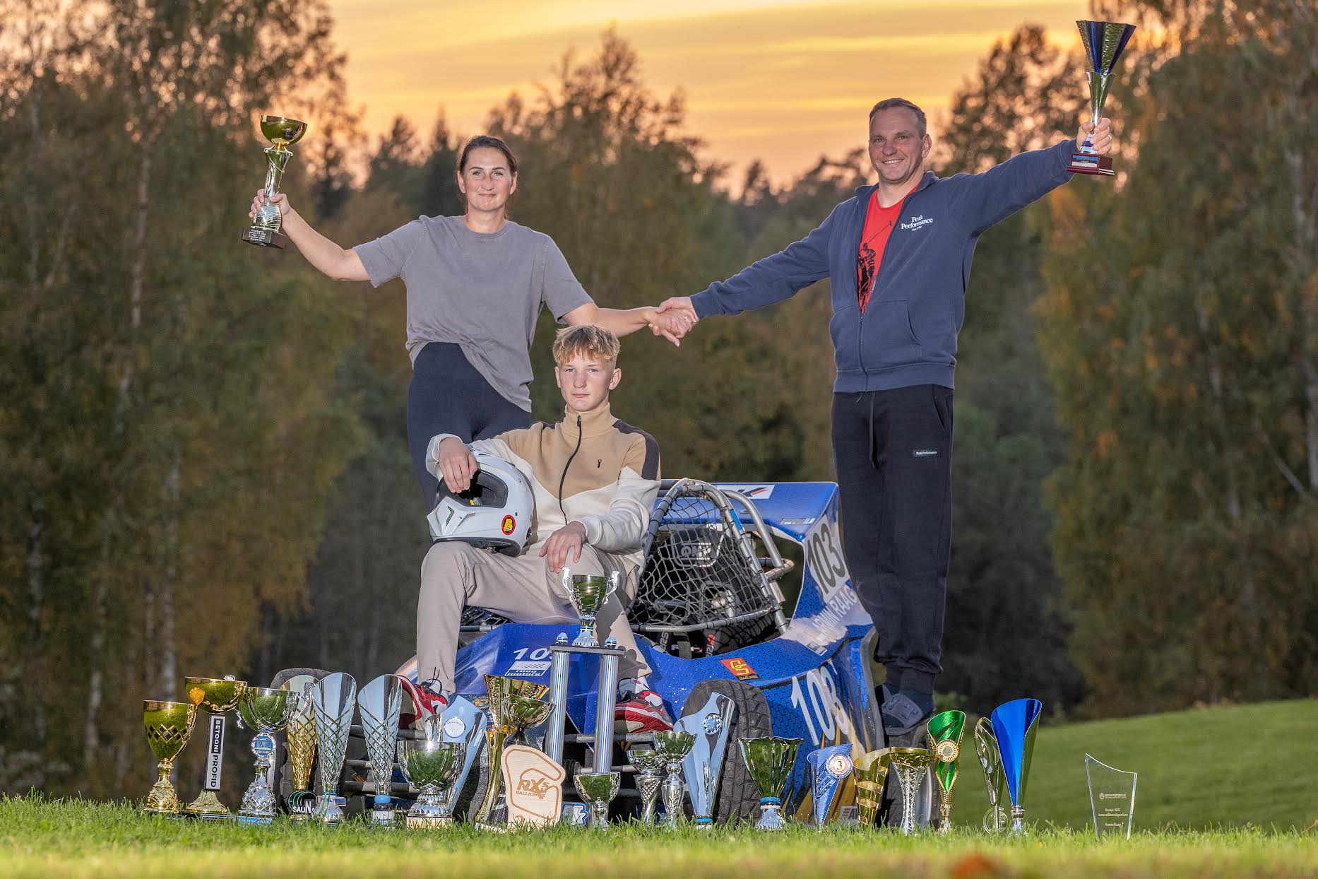 Kahekordne Eesti rallikrossi meister Armin Raag koos isa Armo Raagi ja ema Natalja Fatejevaga. Taustaks sõiduvahend, mis sportlasele juba nii-öelda kitsaks jääb. Möödunud nädalavahetusel võistles Armin Raag juba suurema ning võimsama sõiduriistaga ja saavutas esikoha. Fotot on ehtimas Armini aja jooksul võidetud karikad, mida ühtekokku on tal peaaegu 30. Foto: AIGAR NAGEL