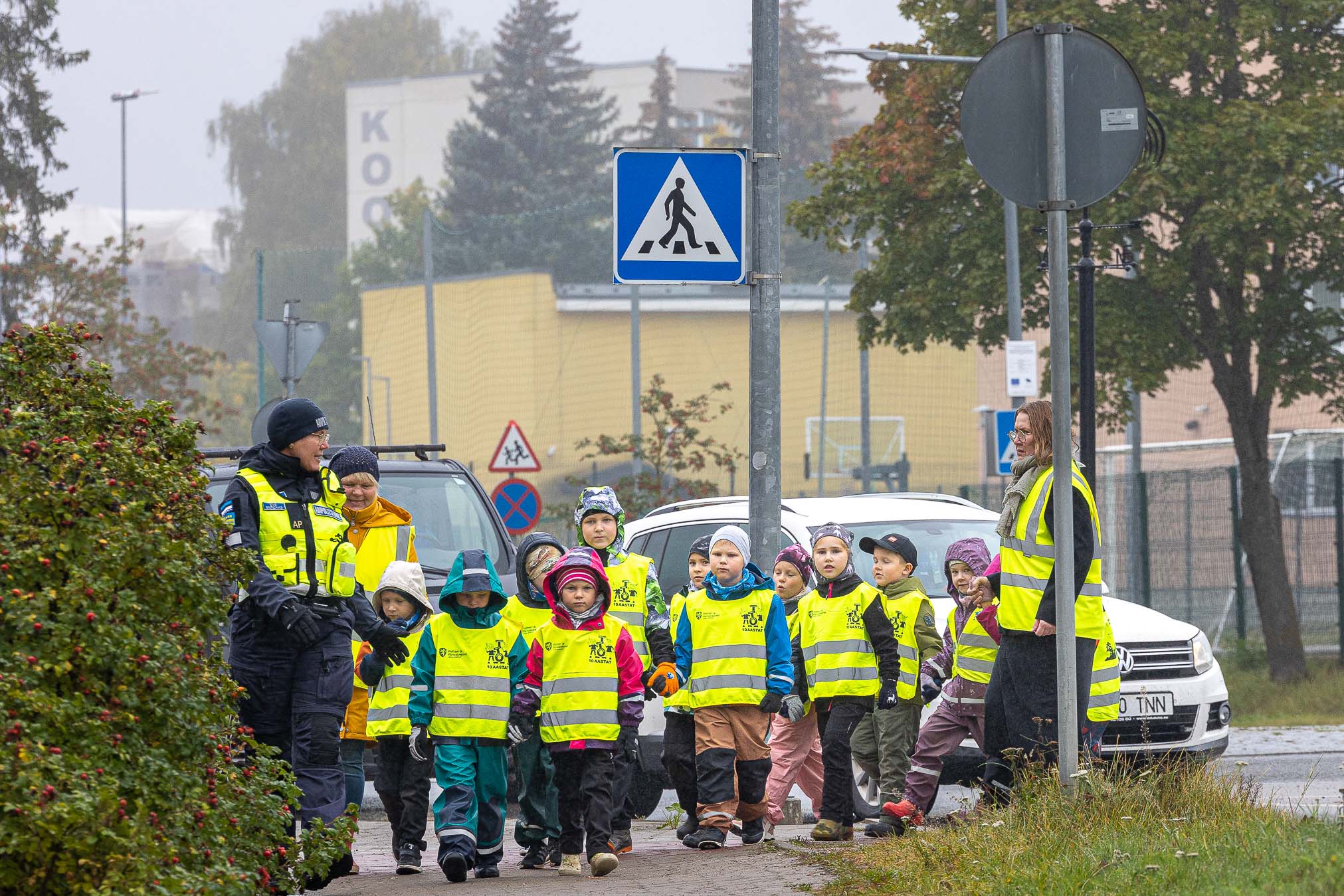 Abipolitseinik Eve Breidaks, Okasroosikese lasteaia lapsed, õpetaja Merle Kendra ning (paremal) juhiabi Anne-Ly Kinsigo Kreutzwaldi kooli juurest Spordikeskuse juurde suundumas. FOTOD: Aigar Nagel