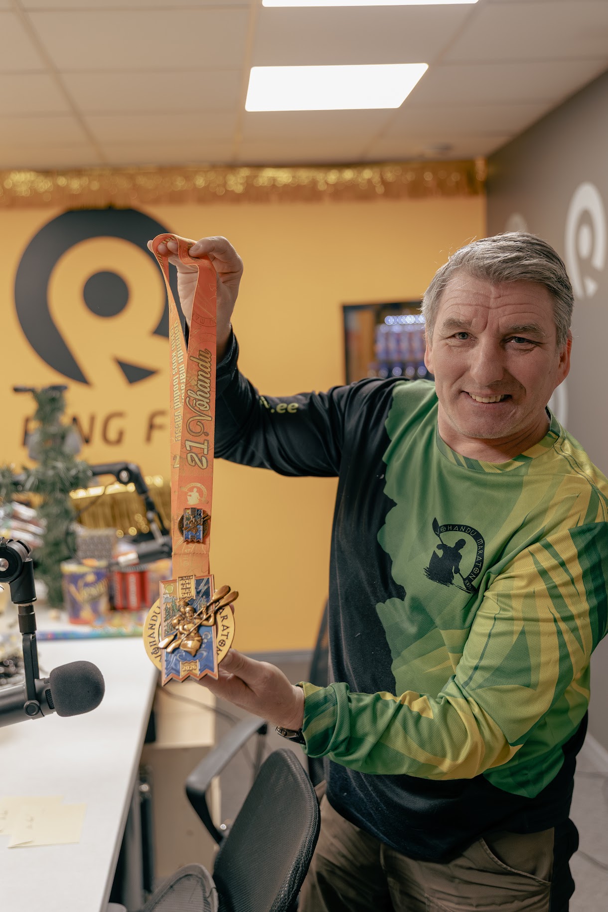 Võhandu maratoni peakorraldaja Hillar Irves 31. detsembril Ring FMi stuudios näitamas 2026. aasta maratoni medalit ja rääkimas medali kujundamise telgitagustest. Fotod: AIGAR NAGEL