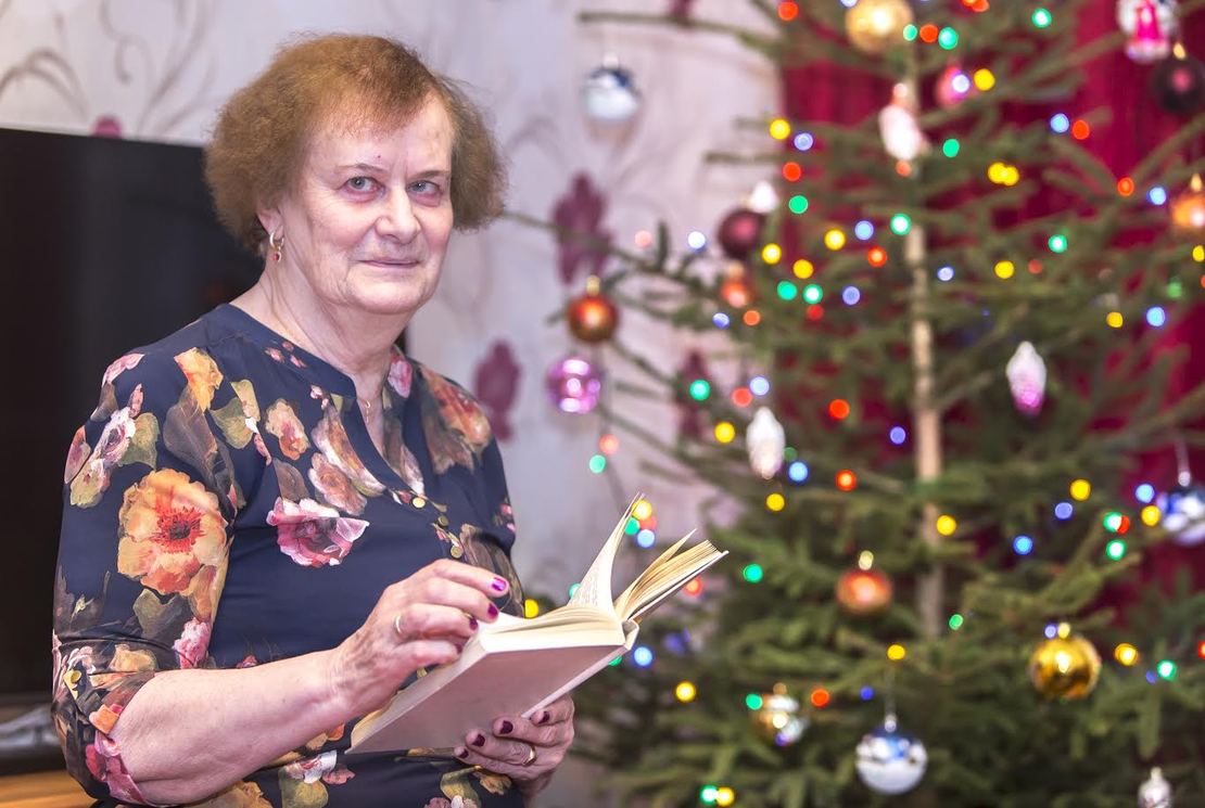 Tiiu Miller koduse jõulupuu ees. Raamatuid on talle meeldinud lugeda lapsest saati, aga nüüd võtab ta tihedamalt kätte ajalehe ning vahel ka ajakirja. Foto: AIGAR NAGEL